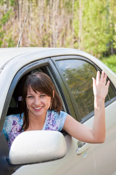 Vrouw een stuurprogramma na het roer van auto golven een hand — Stockfoto