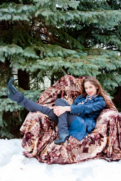 Mulher em uma cadeira ao lado de uma árvore decorativa — Fotografia de Stock