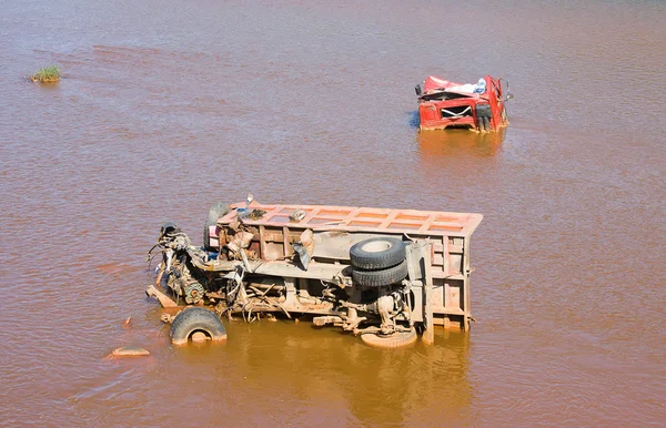 Сломанный грузовик лежит в грязной воде — стоковое фото