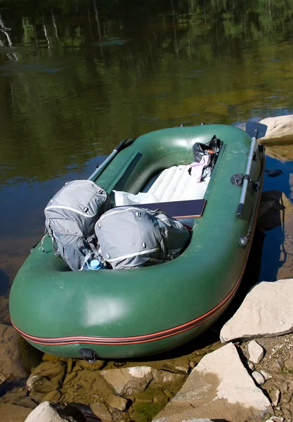 Boot met rugzakken aan oever van de rivier — Stockfoto