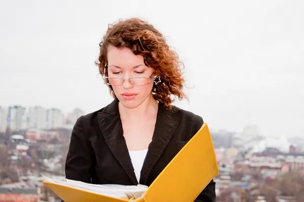 Jeune femme d'affaires avec des documents en main contre — Photo