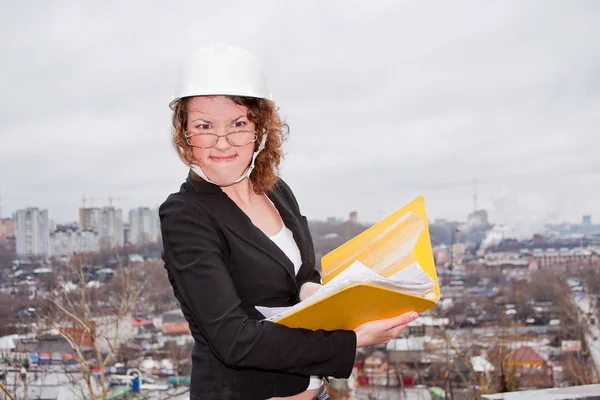 Mulher de negócios jovem em um capacete e documentos em suas mãos — Fotografia de Stock