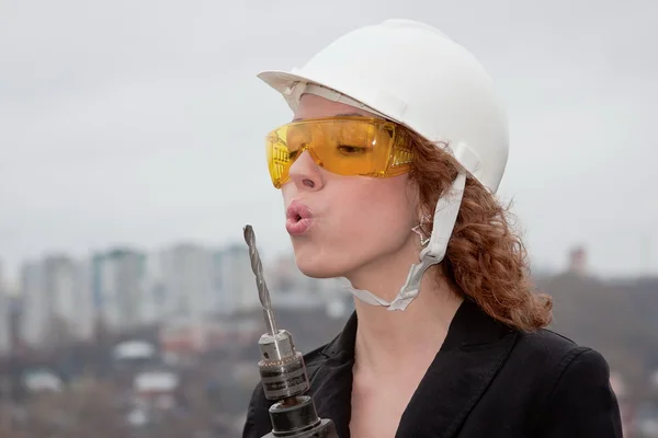 Business woman in a helmet and goggles with a drill in hand Royalty Free Stock Images