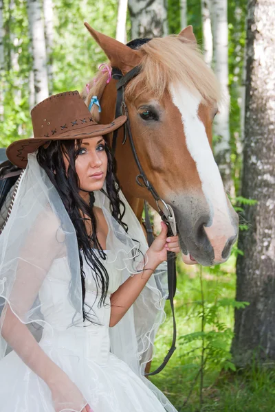 Young woman in the dress of fiancee next to a horse — Stock Photo, Image