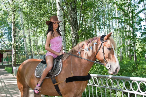 Uma jovem mulher bonita senta-se montado em um cavalo — Fotografia de Stock