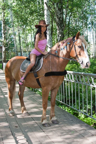 Uma jovem mulher bonita senta-se montado em um cavalo — Fotografia de Stock