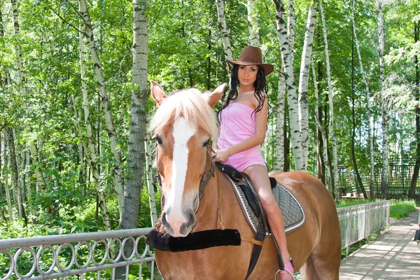 A young beautiful woman sits astride on a horse — Stock Photo, Image