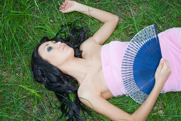 Una joven hermosa mujer en verano en la naturaleza se encuentra en un gras verde — Foto de Stock