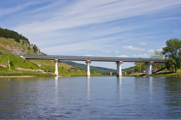 Brücke über den Fluss auf einem Hintergrund schönen blauen Himmel — Stockfoto