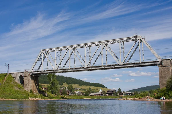 Brücke über den Fluss auf einem Hintergrund schönen blauen Himmel — Stockfoto