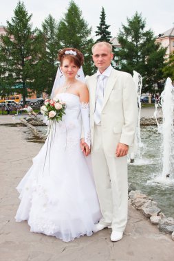 damat ve nişanlısı bir çeşme, bir parkta
