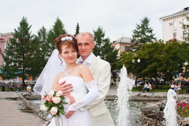damat ve nişanlısı bir çeşme, bir parkta