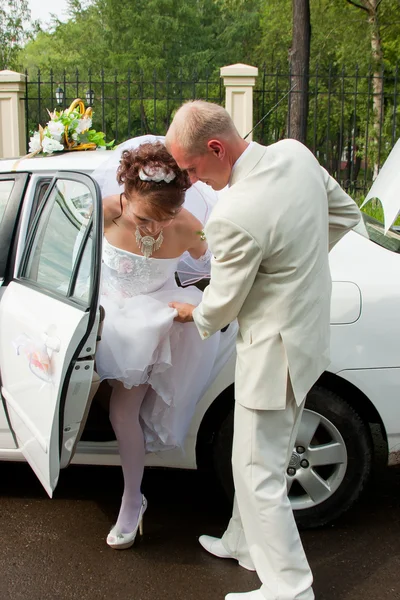 A happy groom and fiancee go out a car — Stock Photo, Image