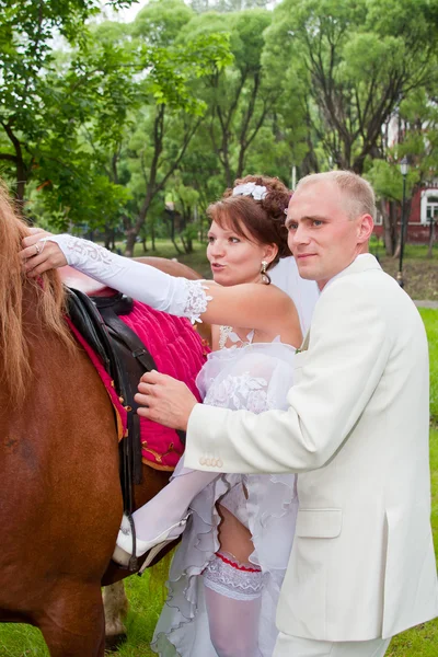 Um noivo e noiva sentam-se em um cavalo — Fotografia de Stock
