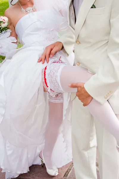 A groom and fiancee show a garter up and about — Stock Photo, Image