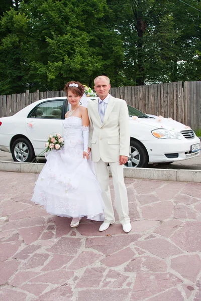 Noivo e noiva em um contexto um carro de casamento — Fotografia de Stock