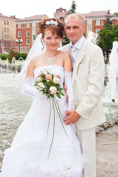 Groom and fiancee in a park at a fountain — Stock Photo, Image