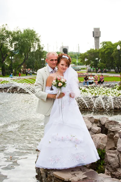 Noivo e noiva em um parque em uma fonte — Fotografia de Stock