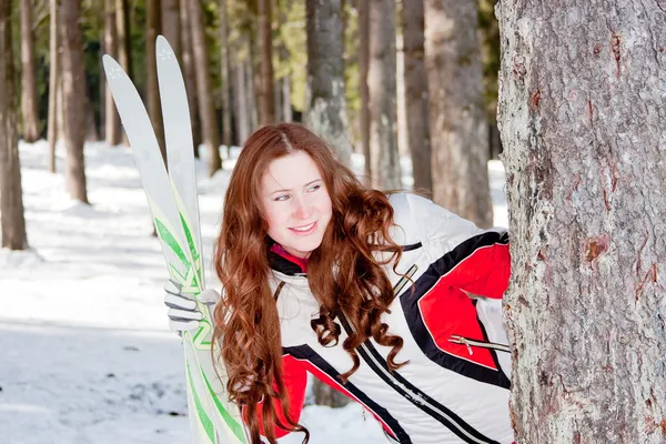 Kvinna i en sport kostym med skidor på fältet — Stockfoto