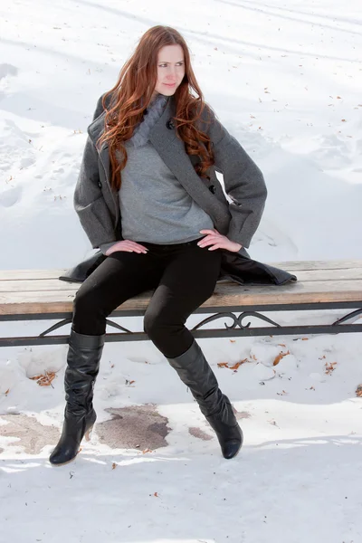 Jeune femme sur un banc en hiver dans un parc — Photo