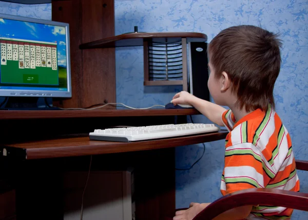 A little boy plays by a computer — Stock Photo, Image