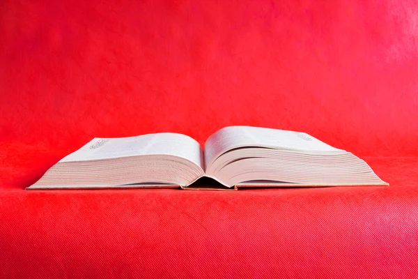 Grand livre ouvert sur fond rouge — Photo