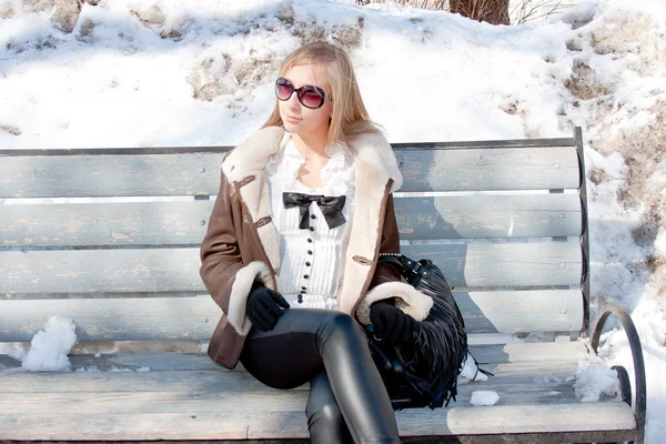 Femme dans un parc d'hiver s'assoit sur un banc — Photo