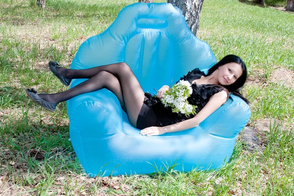 Uma jovem mulher bonita na natureza por um dia ensolarado canicular senta-se — Fotografia de Stock