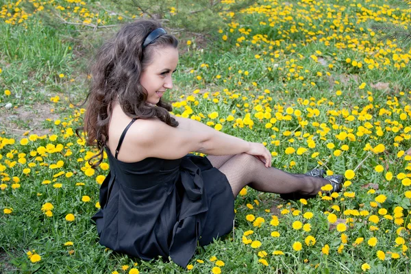 Jovem mulher no gramado florido de dentes-de-leão — Fotografia de Stock