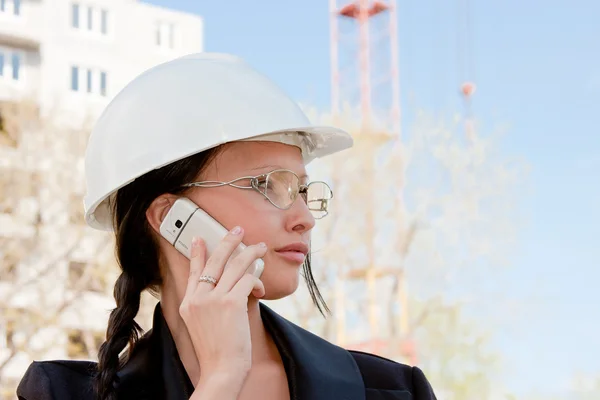 Jeune femme dans un casque et par des documents dans les mains sur un backgrou — Photo