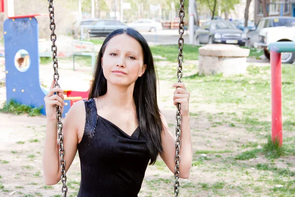 Young beautiful woman on swings in a park — Stock Photo, Image