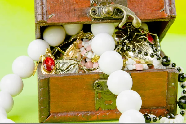 Pequena caixa com tesouros em um fundo verde claro — Fotografia de Stock