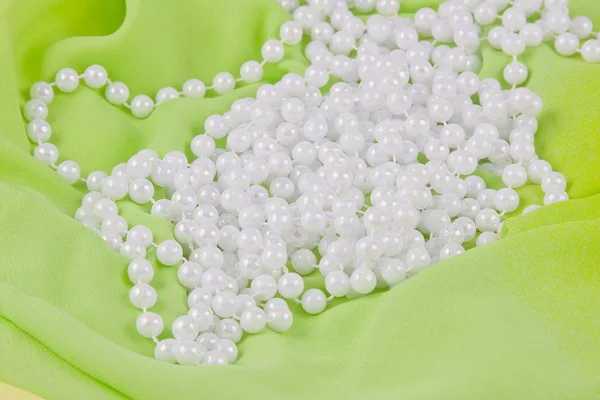 Beads from white pearls on green fabric — Stock Photo, Image
