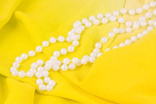 Beads from white pearls on yellow fabric — Stock Photo, Image