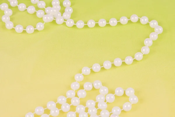 Beads from white pearls on yellow fabric — Stock Photo, Image