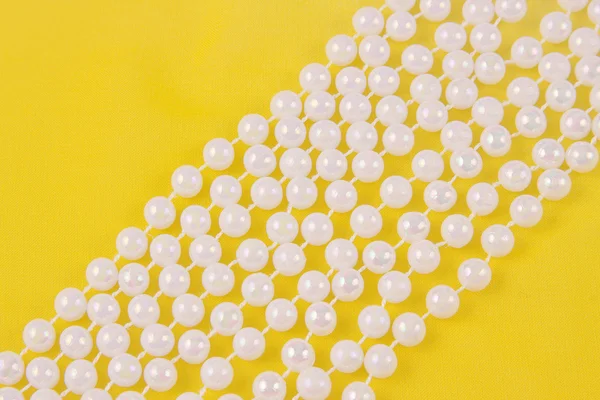 Koraliki z białych pereł na tkaninie żółty — Zdjęcie stockowe