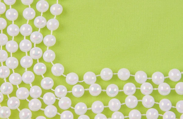 Beads from white pearls on green fabric — Stock Photo, Image