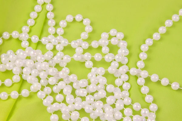 Perles de perles blanches sur tissu vert — Photo