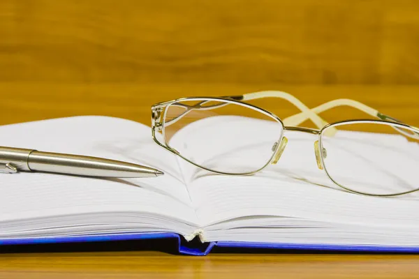 Een notebook, is bril en pen — Stockfoto