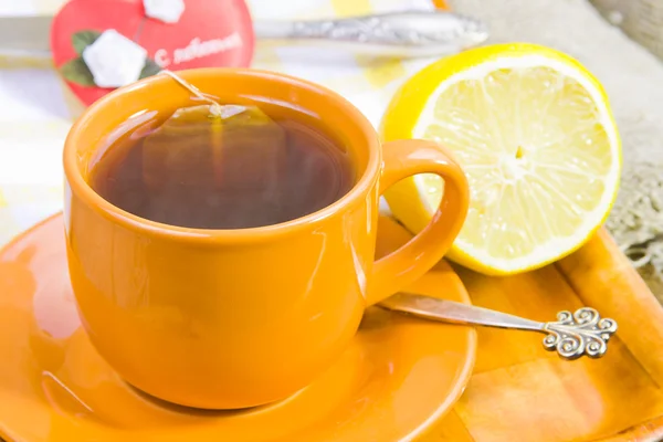 Taza con té, limón y corazón rojo — Foto de Stock