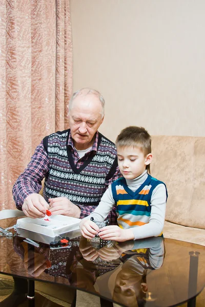 Avô com um neto jogar um designer — Fotografia de Stock