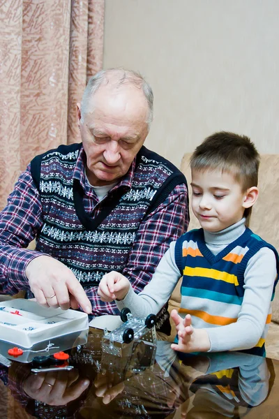 Grand-dad with a grandchild play a designer — Stock Photo, Image