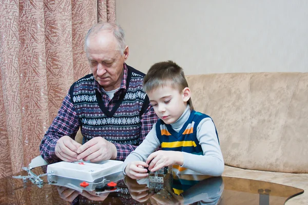 Grand-dad with a grandchild play a designer — Stock Photo, Image