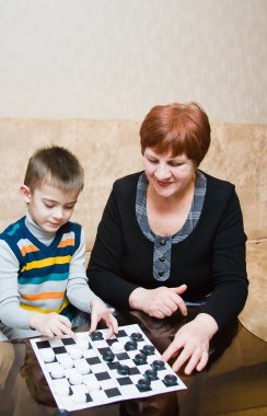 Büyükanne dama bir torun ile oynuyor.