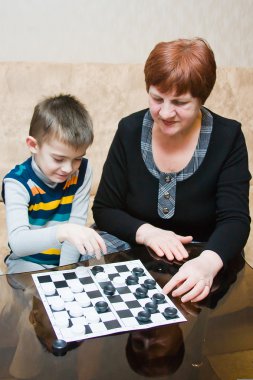 Büyükanne dama bir torun ile oynuyor.