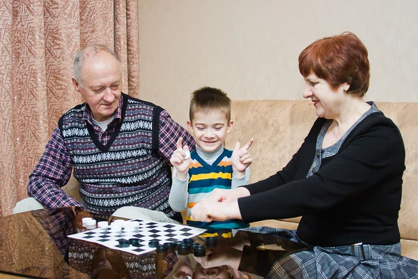 Een grootmoeder, grand-papa, spelen met een kleinkind bij dammen — Stockfoto