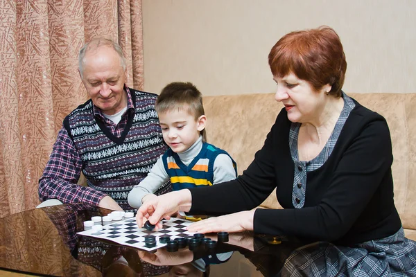 Een grootmoeder, grand-papa, spelen met een kleinkind bij dammen — Stockfoto