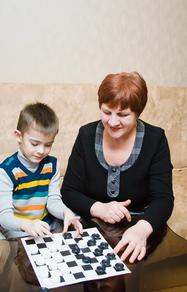 A grandmother plays with a grandchild in checkers — Stock Photo, Image