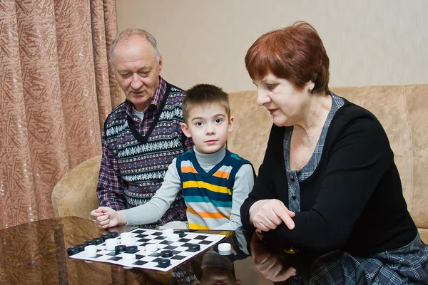 En mormor, grand-pappa, spela med ett barnbarn i brickor — Stockfoto