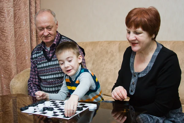 Een grootmoeder, grand-papa, spelen met een kleinkind bij dammen — Stockfoto